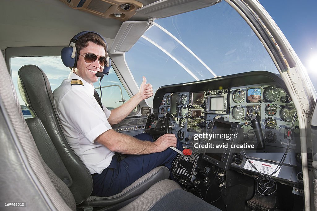 Young pilot in aircraft cockpit giving thumbs up