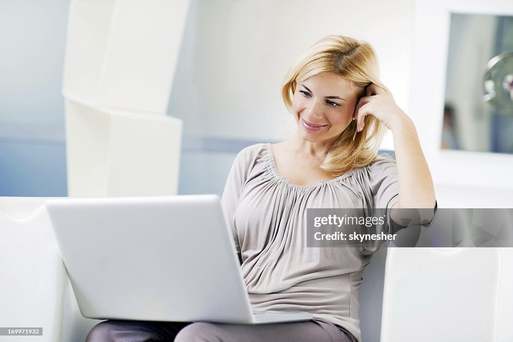 Hermosa mujer joven usando su computadora portátil en su hogar.