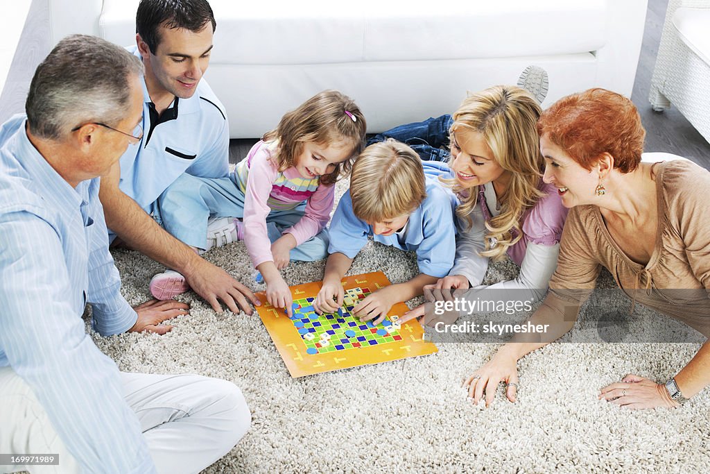 Fröhliche Familie spielen Brettspiel auf dem Boden.