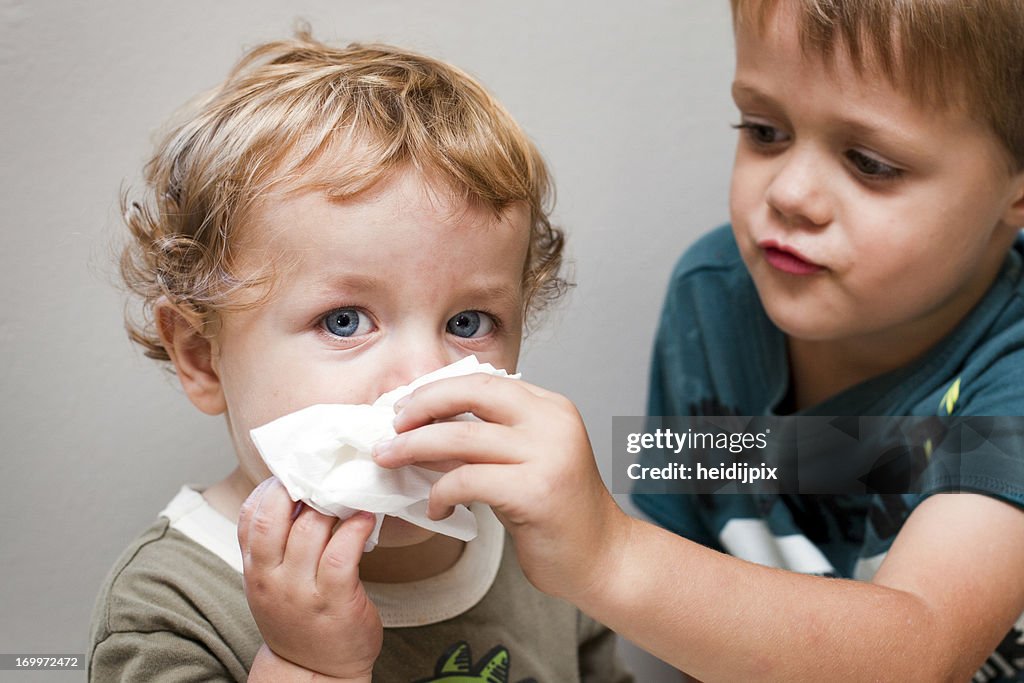 Older boy helping a younger boy blow his nose