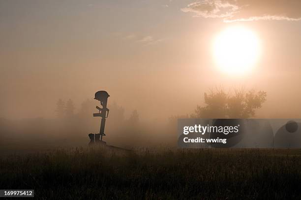 grave of fallen soldier - boots rifle helmet stockfoto's en -beelden