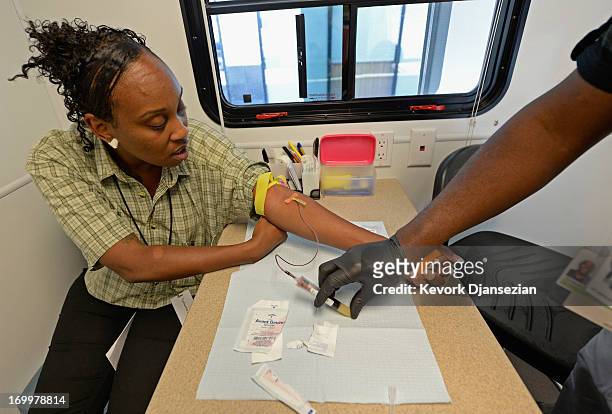 Tyshuanna Jackson get her blood drawn for HIV/AIDS and STD testing by Ernest Johnson of John Wesley Community Health Institute in one of their mobile...