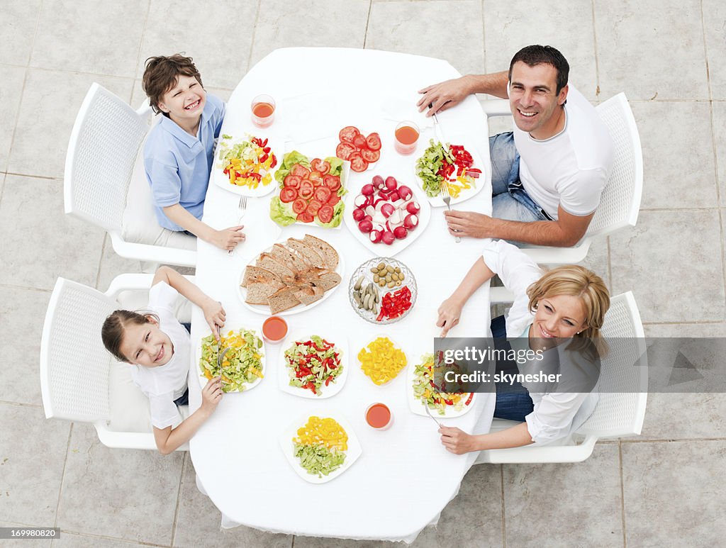 Happy family eating together outdoor.