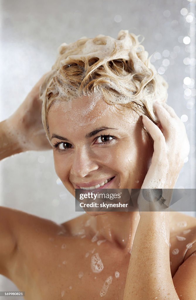 Pretty beautiful woman washing her hair in a shower.