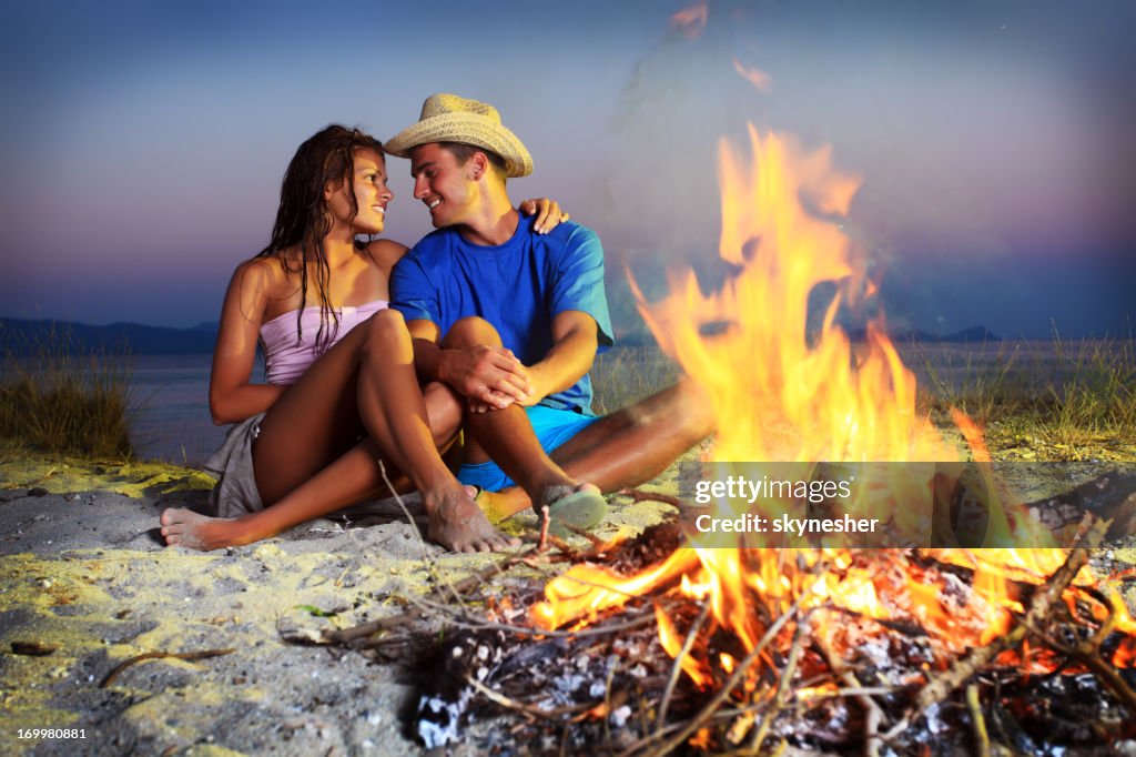 Couple enjoying themselves next to the campfire.