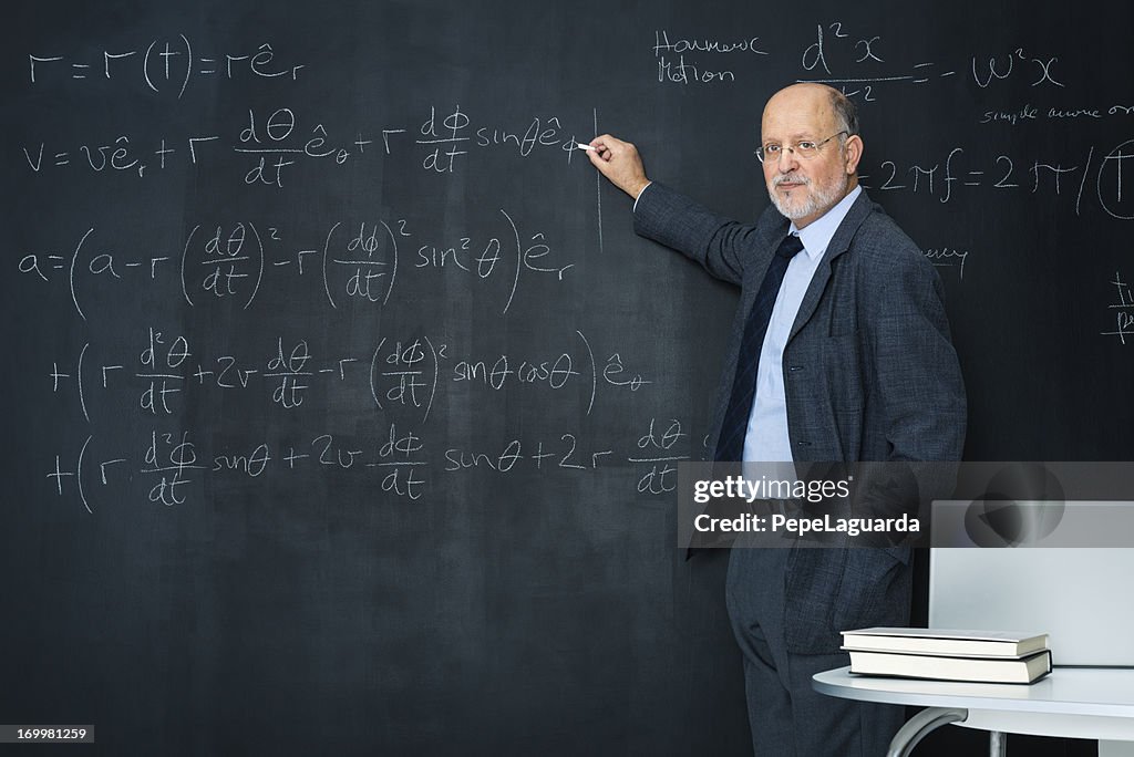 Science teacher writting at blackboard physics equation
