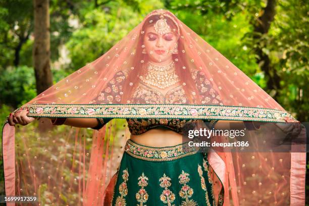beautiful traditional indian bridal wearing lehenga and jewelry in outdoor. - indian bridal makeup stock pictures, royalty-free photos & images