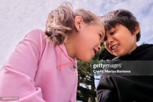brother and sister sit forehead to forehead and make funny faces at each other. - butting stock pictures, royalty-free photos & images