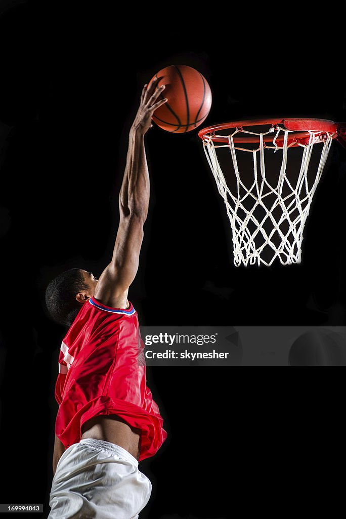 Basketball player slam dunking the ball.