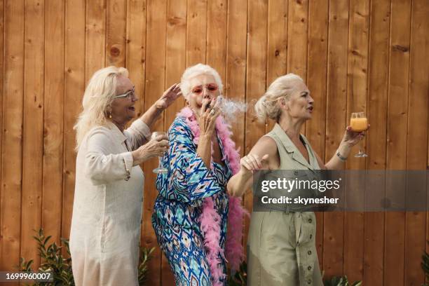 unbeschwerte ältere frauen, die auf einer party gegen den zaun tanzen. - coole oma stock-fotos und bilder