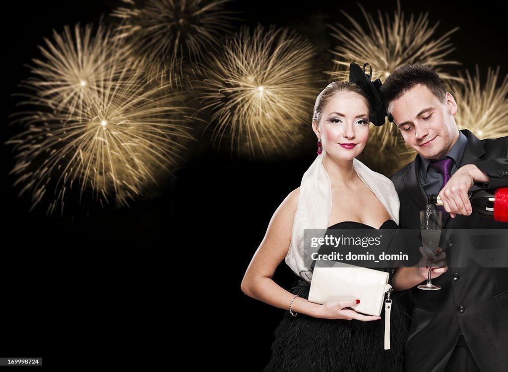 New Year's couple with glass of champagne against fireworks, night