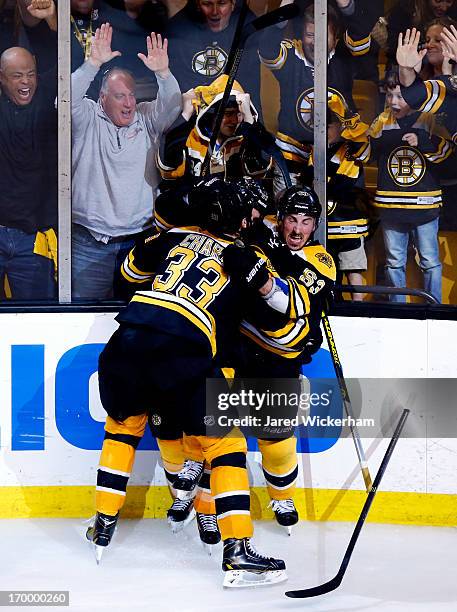 Patrice Bergeron of the Boston Bruins celebrates with Brad Marchand and Zdeno Chara after scoring the game winning goal in overtime to beat the...