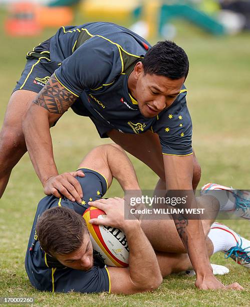 Australian Wallabies fullback Israel Folau stands over centre Rob Horne during a team training session in Sydney on June 6, 2013. The Wallabies are...