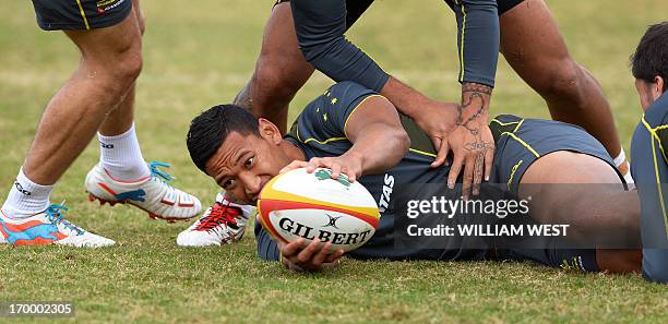 Australian Wallabies fullback Israel Folau presents the ball in a drill during a team training session in Sydney on June 6, 2013. The Wallabies are...