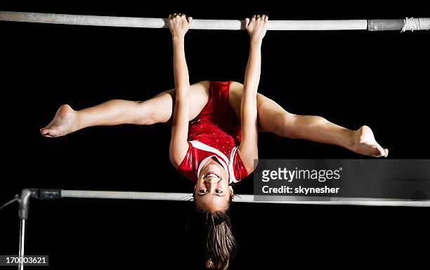 strong gymnast girl exercising on uneven bars. - brug turntoestel stockfoto's en -beelden