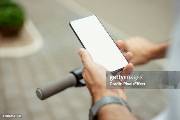 over shoulder view of man holding phone mockup white screen while driving electric scooter - white shirt template stock pictures, royalty-free photos & images