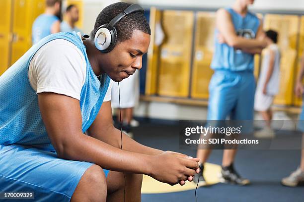 serious basketball player listening to music in locker room - high school locker room stock pictures, royalty-free photos & images