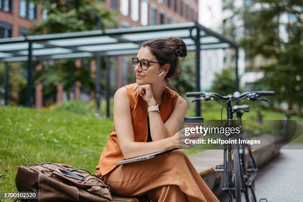 portrait of young urban woman sitting outdoors in the city. - in ear headphones stock pictures, royalty-free photos & images