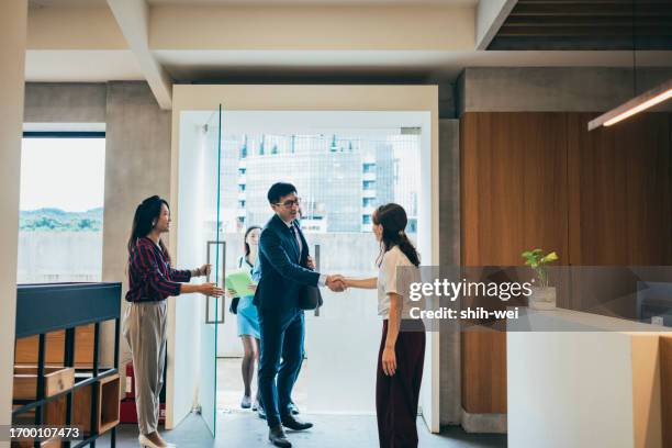 the asian female executive welcomes the team from the collaborating company, and the two executives shake hands upon entering, preparing to commence negotiations on cooperation matters. - matters stock pictures, royalty-free photos & images