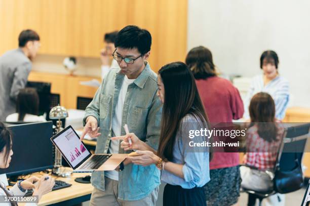 ein asiatischer mann führt eine diskussion mit seinen kollegen in einem kreativbüro, in der sie gemeinsam brainstormen, herausforderungen meistern und lösungen finden. - brainstormen stock-fotos und bilder