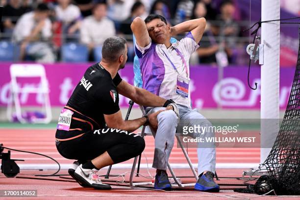 In this picture taken on September 30 an official reacts in pain after his leg was injured by a stray hammer thrown by Ali Zankawi who attempts to...