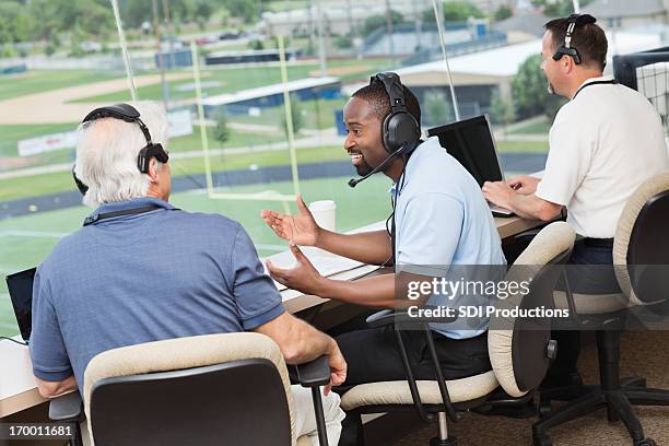 a group of football commentators sitting at a desk - commentator stockfoto's en -beelden