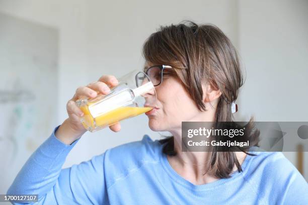 elderly woman drinking fresh juice in the kitchen - woman drinking juice stock pictures, royalty-free photos & images