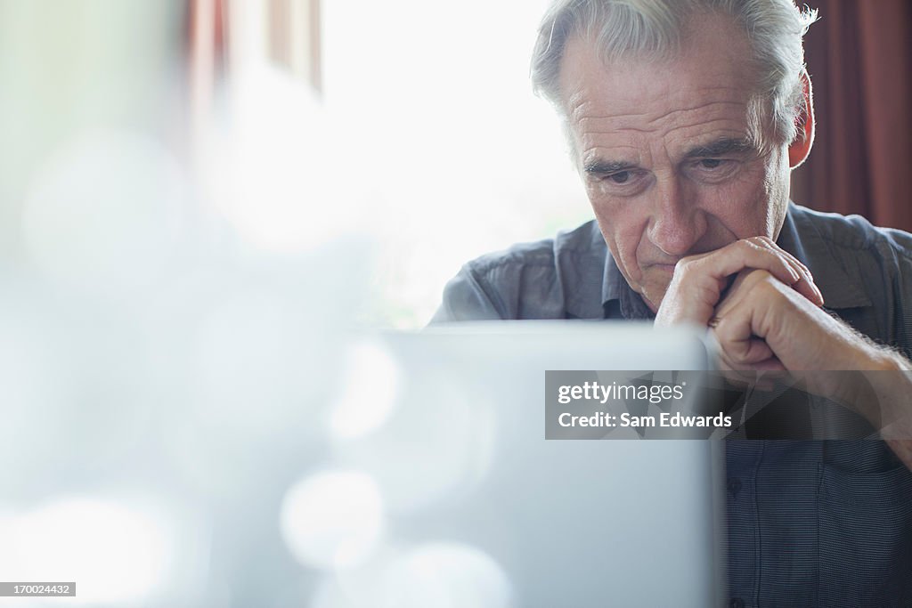 Senior hombre con las manos juntas con capacidad para computadora portátil