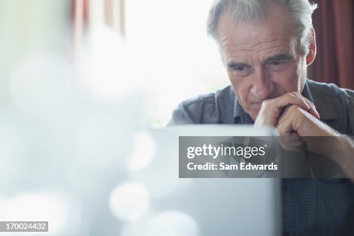 Senior man with hands clasped using laptop Senior man with hands clasped using laptop