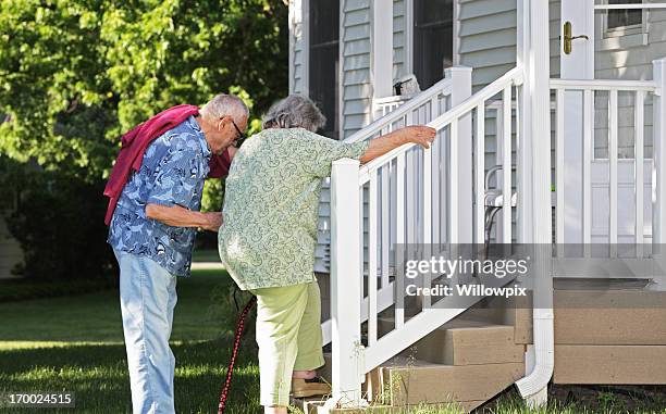 senior man helping wife climb stairs - human settlement stock pictures, royalty-free photos & images