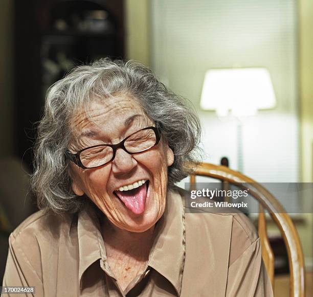 senior woman sticking tongue out - tongue out stockfoto's en -beelden