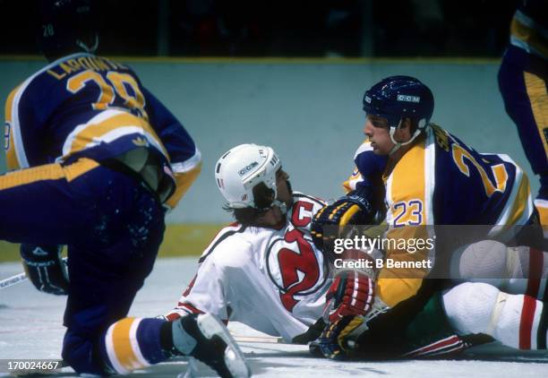 Doug Smith of the Los Angeles Kings tackles Mel Bridgman of the New Jersey Devils on February 21, 1985 at the Brendan Byrne Arena in East Rutherford,...