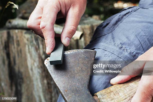 man sharpening axe with whetstone - steniging stockfoto's en -beelden