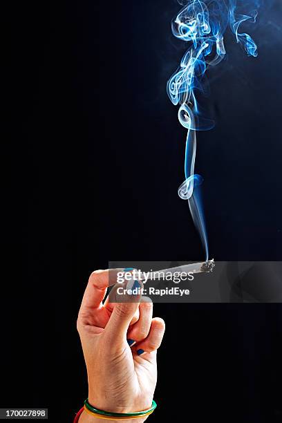 female hand holding lit marijuana cigarette - stick stockfoto's en -beelden