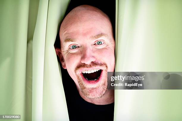 excited man looks through closed curtains with a beaming smile - rea001 stock pictures, royalty-free photos & images