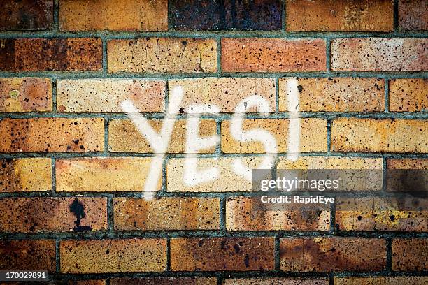 yes! says enthusiastic graffiti on grungy brick wall - yes stock pictures, royalty-free photos & images