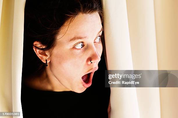 wide-eyed, shocked woman peeping out: what are the neighbours doing? - nosy woman bildbanksfoton och bilder