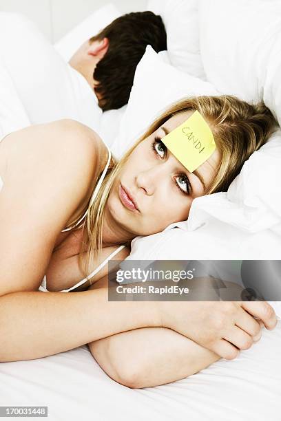 young woman wearing name tag in bed with uncaring man - promiscuous woman stock pictures, royalty-free photos & images