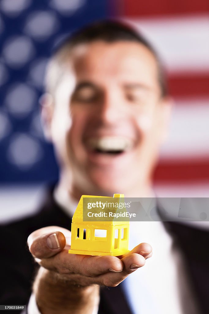 Casa de Brinquedo na posse homem com a bandeira americana no fundo