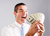 Triumphant businessman counting fistful of dollars gleefully