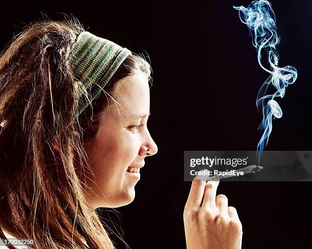 smiling young rasta girl holds hand-rolled reefer - human joint stockfoto's en -beelden