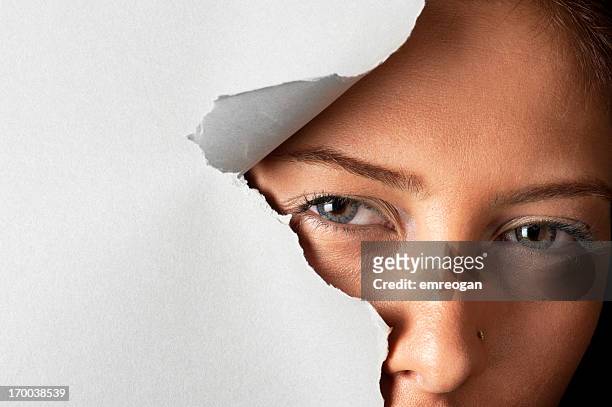 young woman looking out through hole - tear face stock pictures, royalty-free photos & images