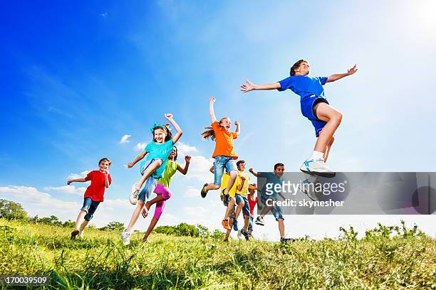 cheerful kids jumping in field against the sky. - kids exercising stock pictures, royalty-free photos & images