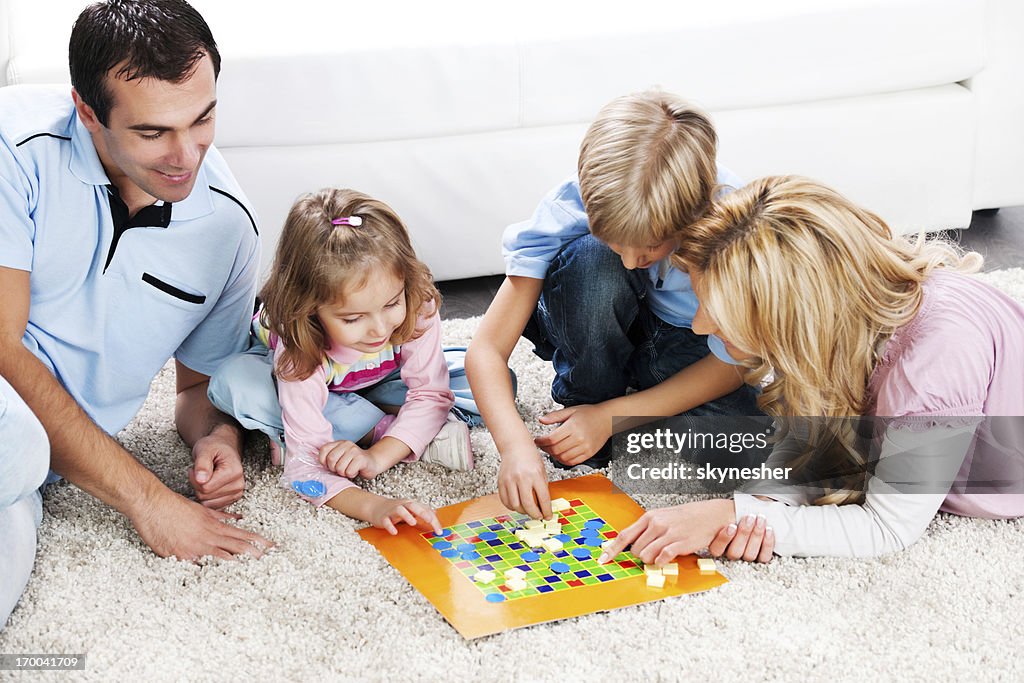 Cheerful parents playing board game with their children.