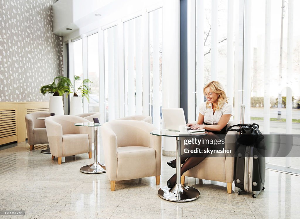 Business woman using her laptop in a hotel lobby.