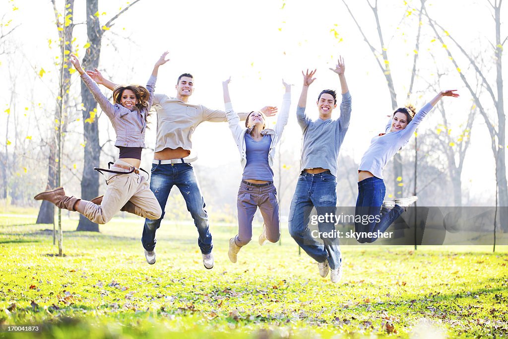 Smiling group of teenagers jumping in the mature.