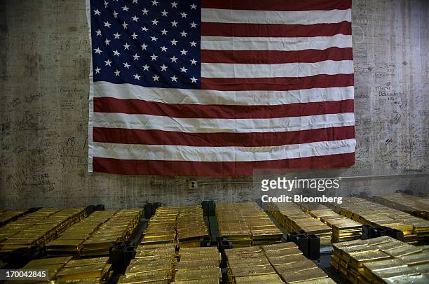 The US flag hangs over gold bars in a vault at the United States Mint at West Point in West Point, New York, U.S., on Wednesday, June 5, 2013. Sales...