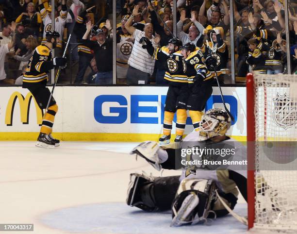 Patrice Bergeron of the Boston Bruins celebrates with Brad Marchand and Zdeno Chara after scoring the game winning goal against Tomas Vokoun of the...