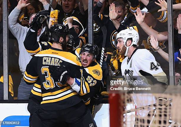 Patrice Bergeron of the Boston Bruins celebrates with Brad Marchand and Zdeno Chara as Brooks Orpik of the Pittsburgh Penguins leaves the ice after...