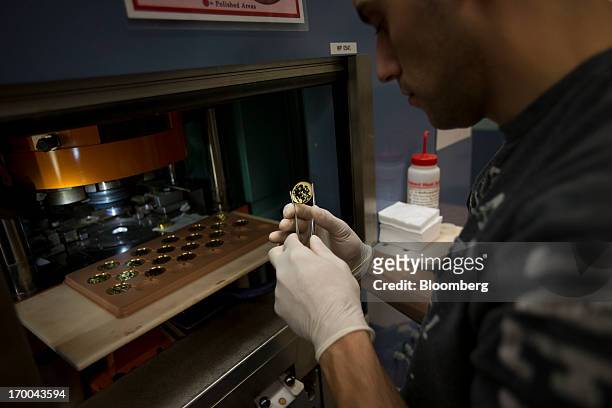 Die Setter Justin Pagan inspects a gold coin at the United States Mint at West Point in West Point, New York, U.S., on Wednesday, June 5, 2013. Sales...